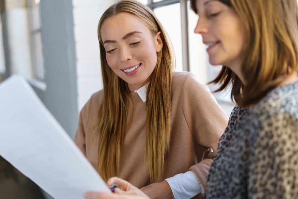 two-businesswomen-standing-front-office-window