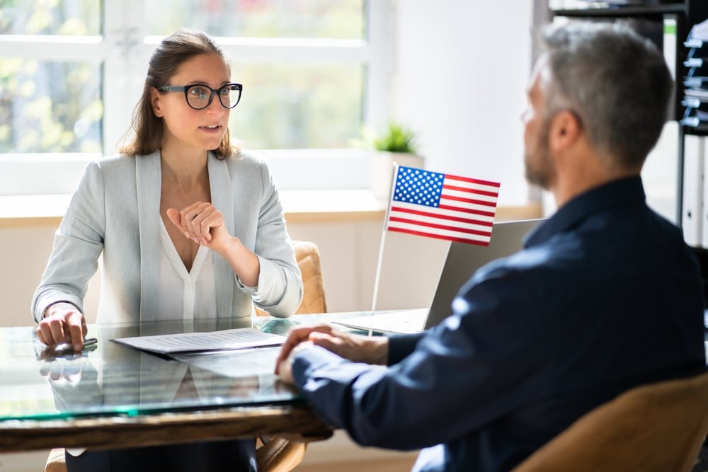 Woman talking to man at desk with US flag