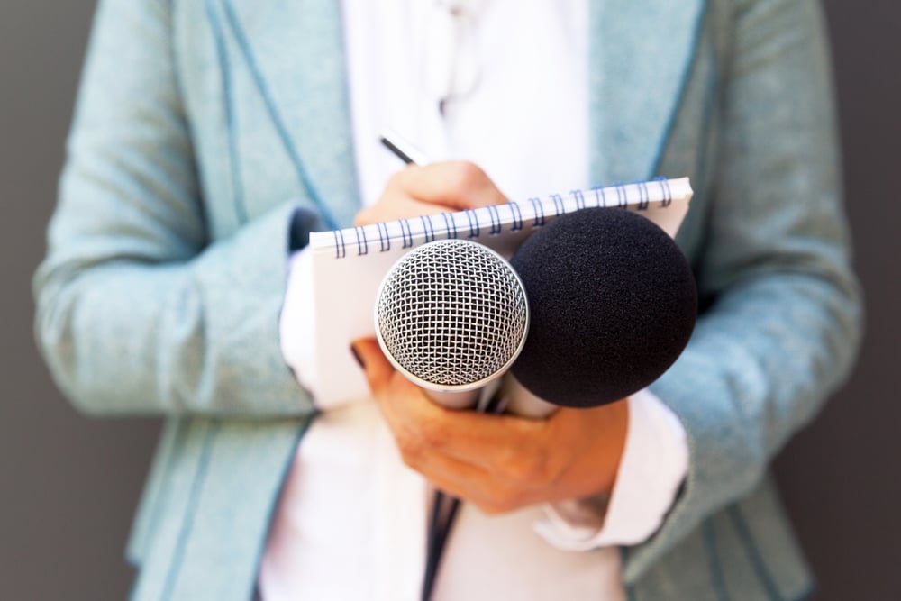 Woman holding microphones and notepad