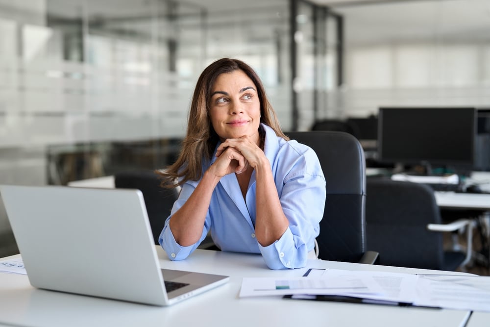 business woman at desk with laptop and papers