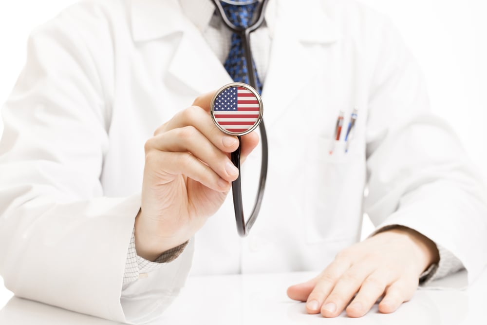 physician holding stethoscope with american flag