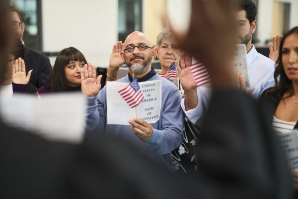 Group of people in a ceremony taking the United States Naturalization Oath of Allegiance to become citizens.