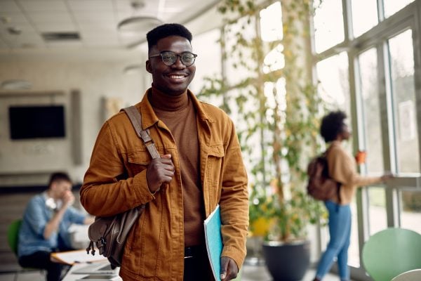 A young college student stands smiling as he prepares to begin his F-1 visa program.