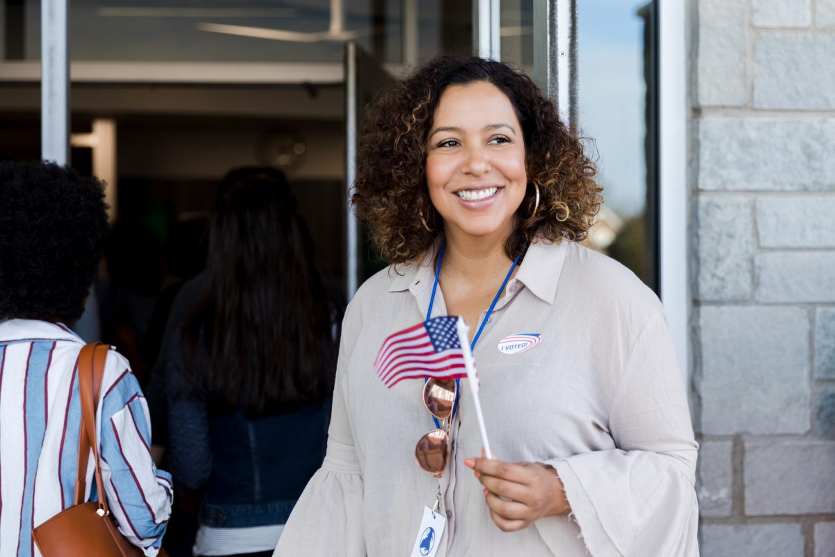 A proud woman waves a small U.S. flag on election day.