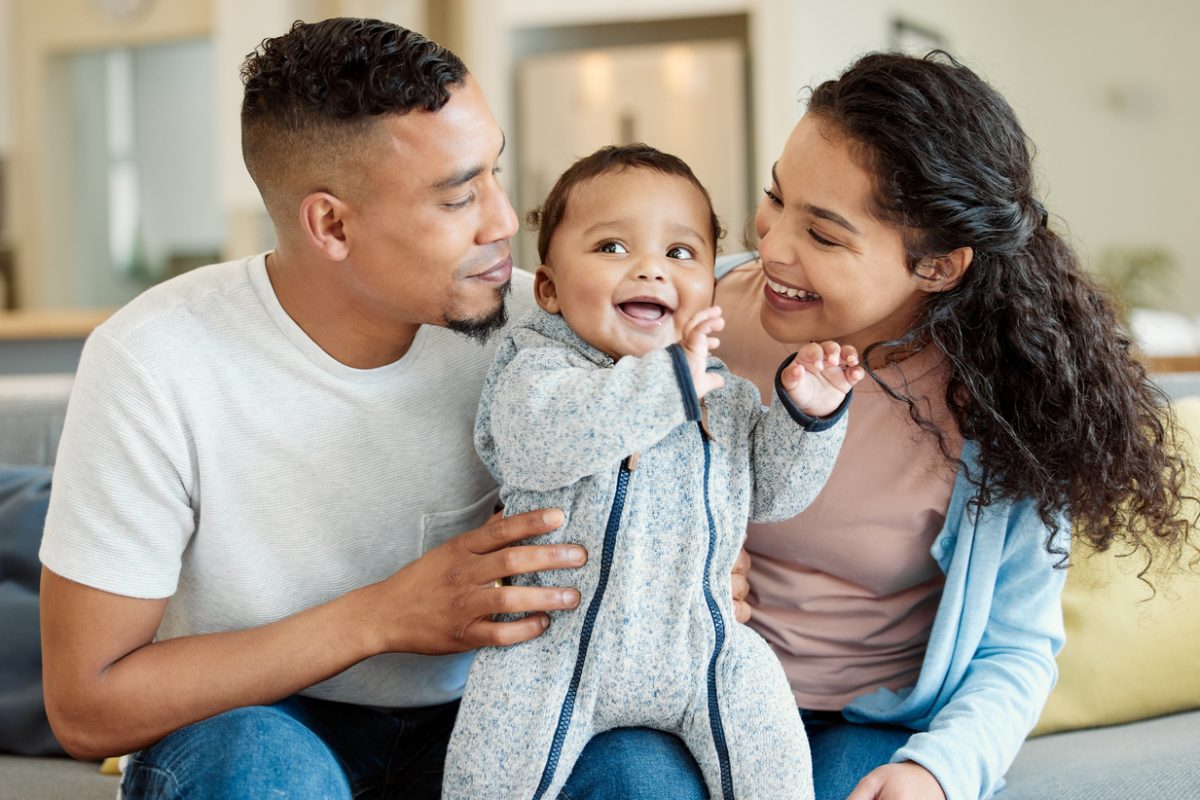 A young married couple smiling with their child.