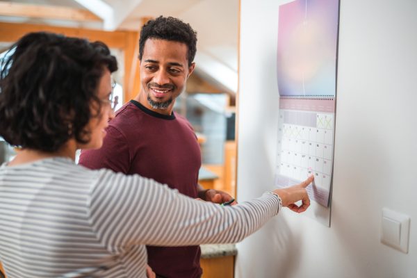 Couple looking at a calendar together with a date circled.