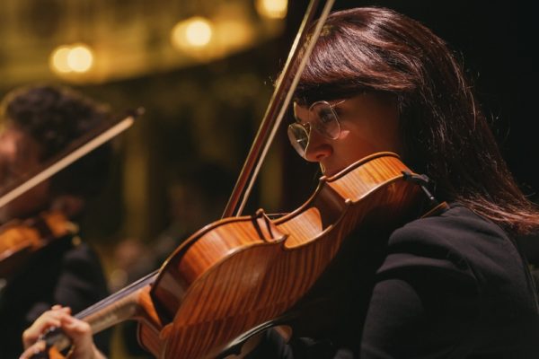 Closeup image of a violinist playing in a concert.