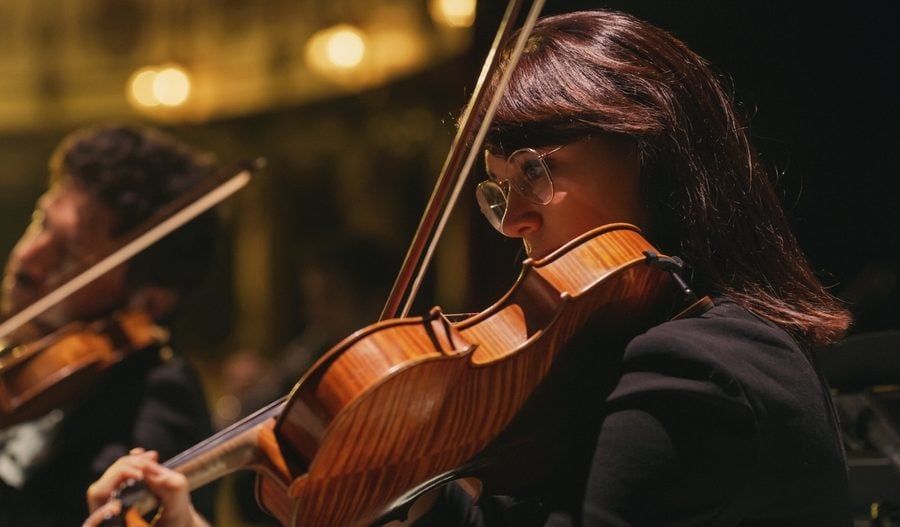 Closeup image of a violinist playing in a concert.