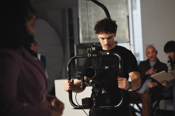 Cinematographer holding an image stabilizer device on a production set.