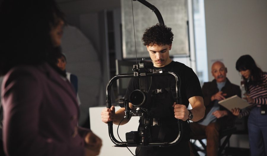 Cinematographer holding an image stabilizer device on a production set.