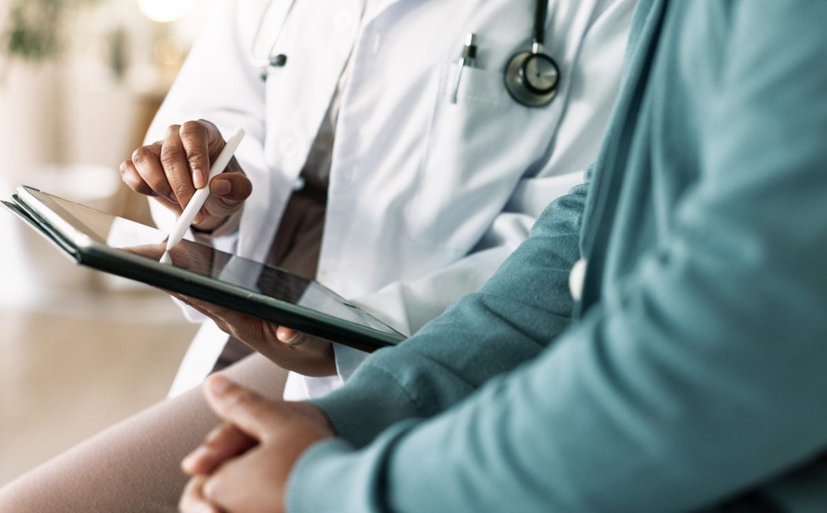 Closeup of doctor's hands reviewing a medical examination report with a patient.
