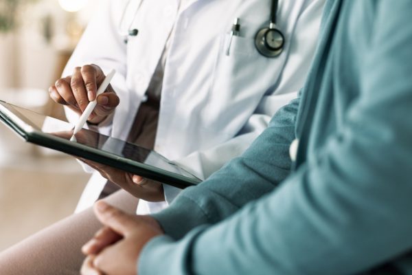 Closeup of doctor's hands reviewing a medical examination report with a patient.
