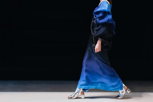 Fashion model on a walking the runway in a blue designer dress.
