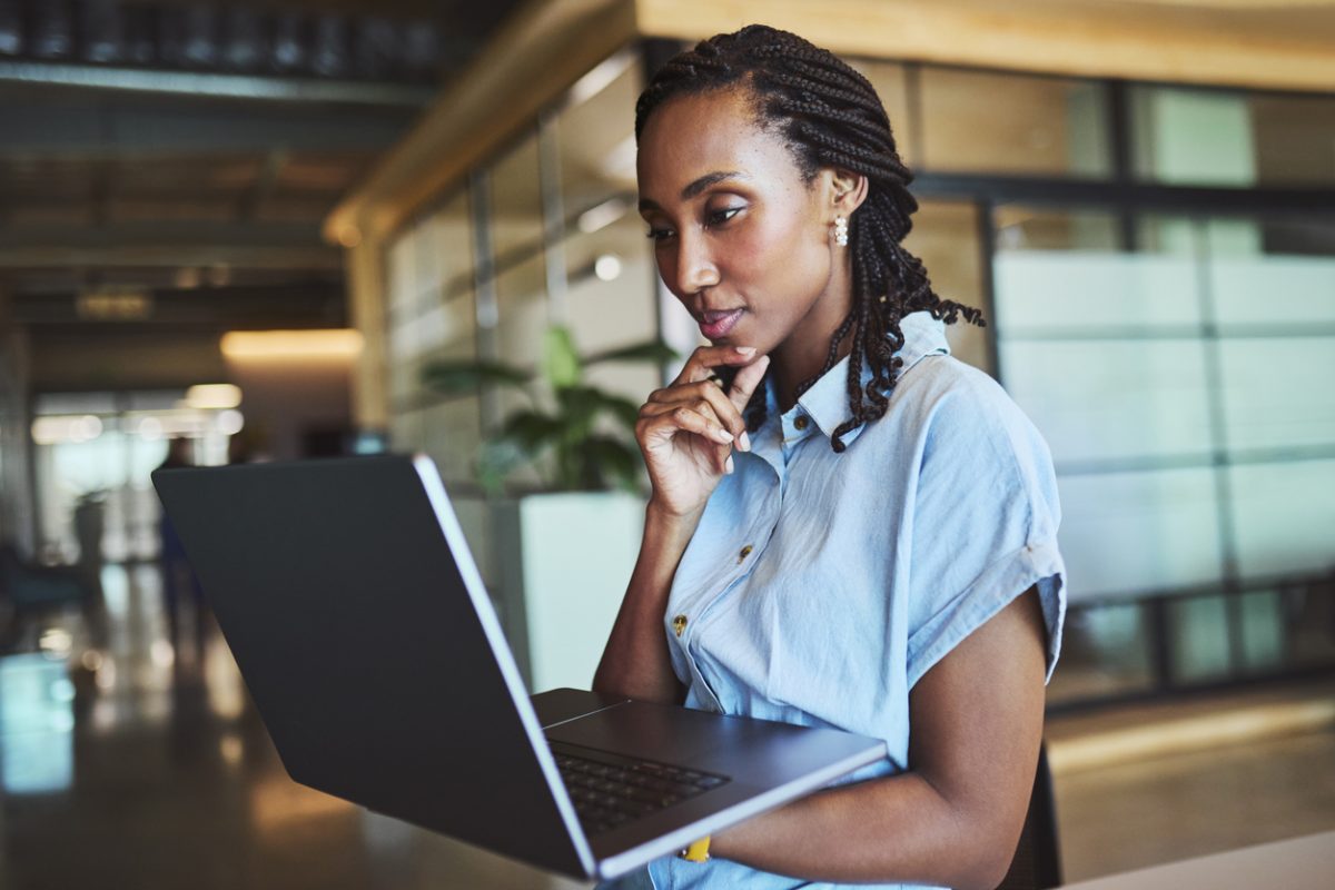 Female worker in modern office looking for information on her laptop screen.