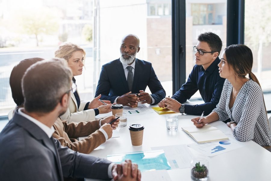 Office workers sitting around a desk in a conference room for a meeting