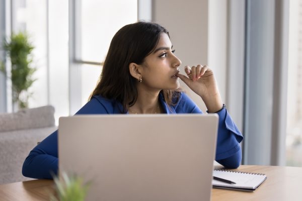 Worker in a startup office with her laptop with a serious expression on her face.