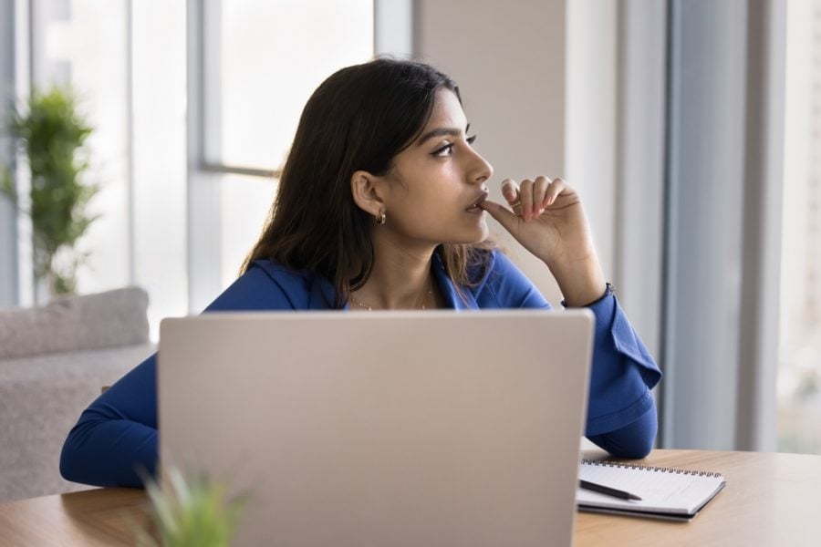 Worker in a startup office with her laptop with a serious expression on her face.