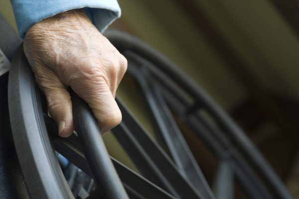 Closeup of a senior citizen's hand on a wheelchair.