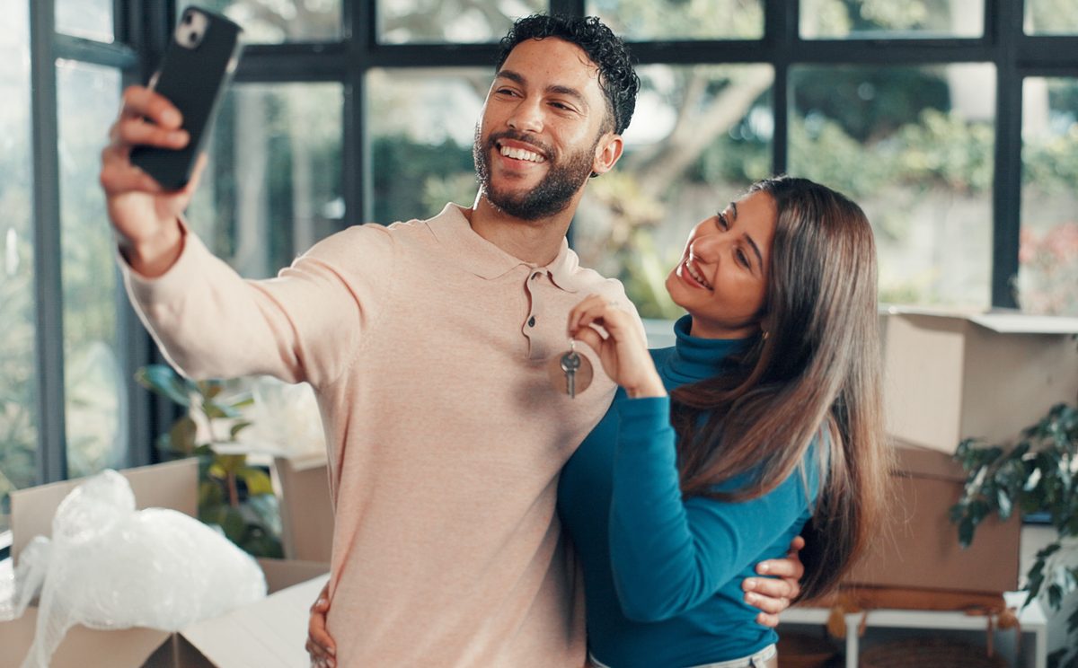 Couple taking a taking a selfie displaying the keys to their new home.