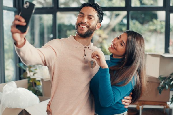 Couple taking a taking a selfie displaying the keys to their new home.