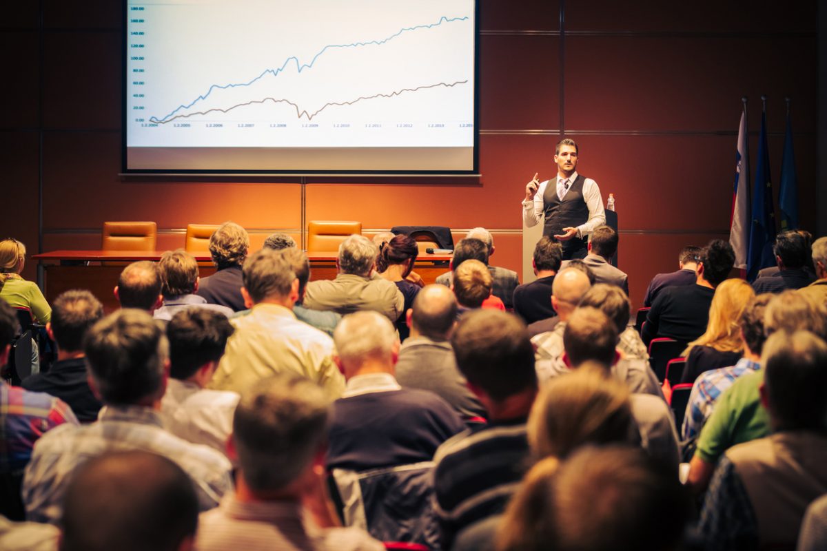 Executive presenting in front of a large audience at a conference.