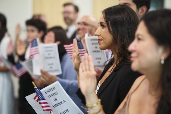 A diverse group of people in a ceremony taking the United States Naturalization Oath of Allegiance to become citizens.
