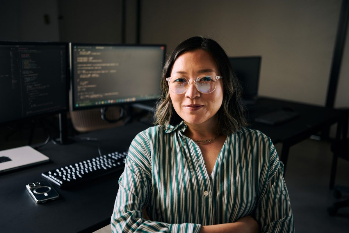 Software engineer sitting in front of monitors displaying her code.