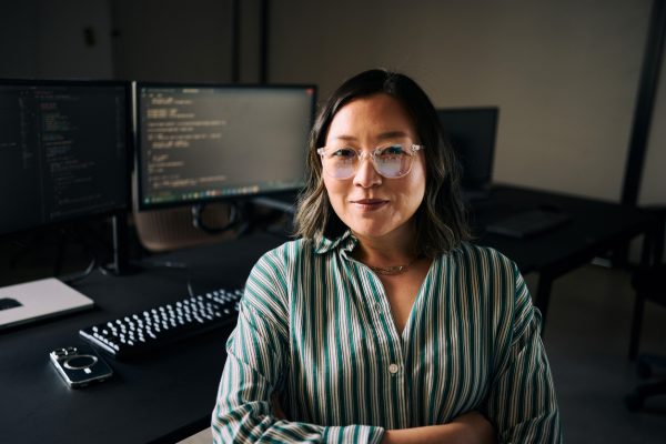 Software engineer sitting in front of monitors displaying her code.