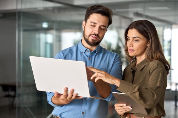 White-collar professionals looking at a laptop together in the office.