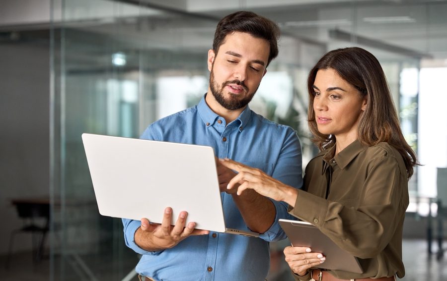 White-collar professionals looking at a laptop together in the office.