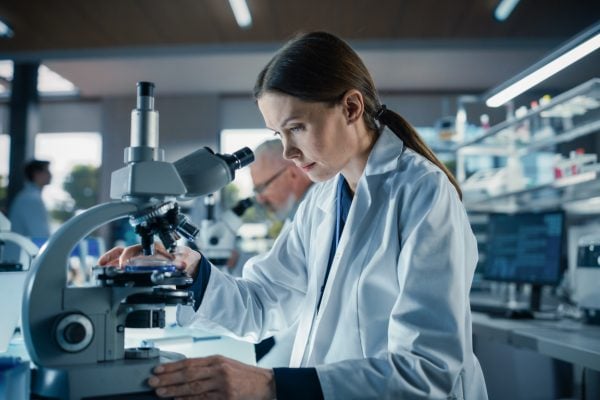 Bioengineer looking at DNA samples under a microscope in her lab.