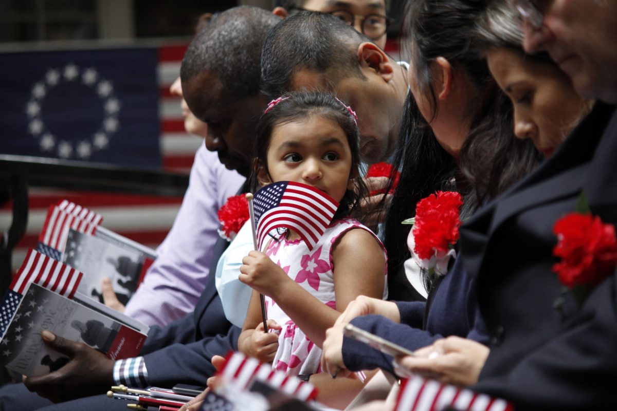 Young girl holding an American flag and sitting with her family at an event.