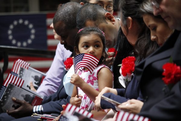 Young girl holding an American flag and sitting with her family at an event.
