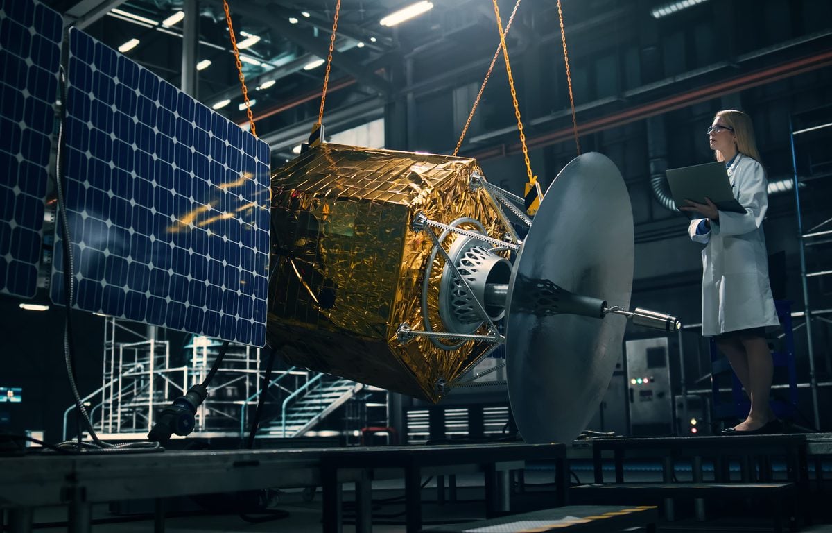 Industrial engineer working on model of satellite in lab.
