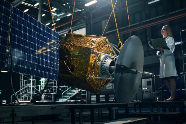 Industrial engineer working on model of satellite in lab.