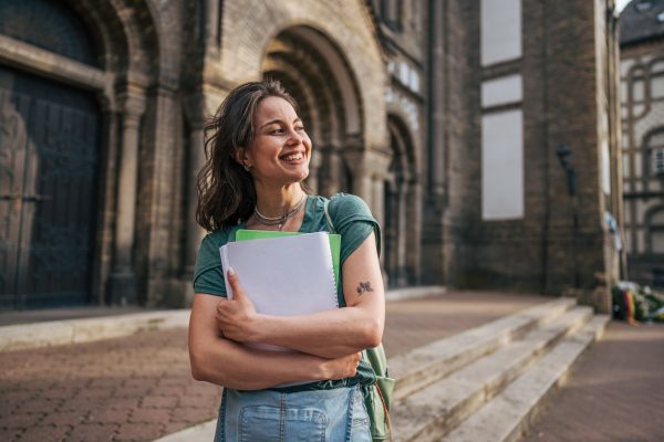 University student on campus holding her notebooks.