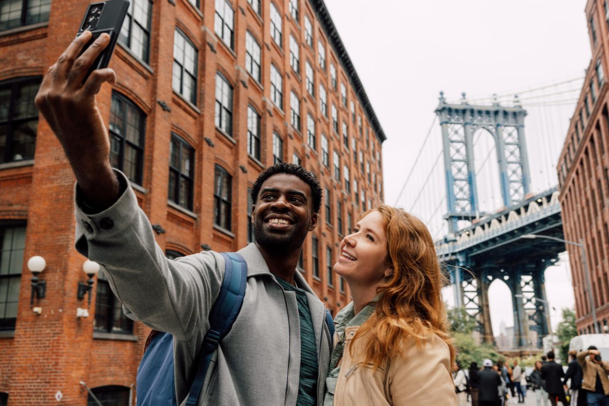 Tourists in the U.S. taking a selfie near the Brooklyn Bridge.